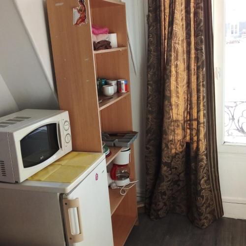 d'un four micro-ondes au-dessus d'un réfrigérateur à côté d'une fenêtre. dans l'établissement STUDIO ST MICHEL, à Paris