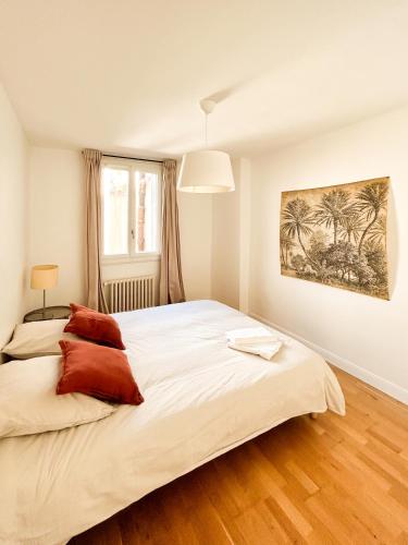 une chambre avec un grand lit blanc avec des oreillers rouges dans l'établissement Jeu De Paume, à Montpellier