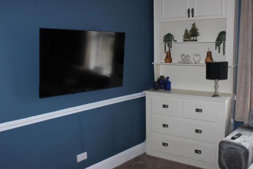 a living room with a tv on a blue wall at Beautiful 7 Bedroom House With Hot Tub Sleeps 14 in Great Ouseburn