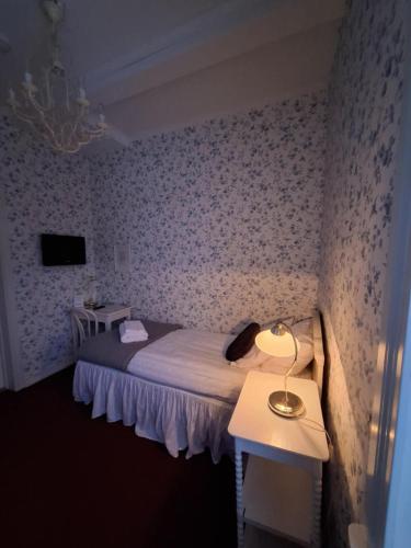 a bedroom with a bed and a table with a lamp at Hotell Örnen in Torsby