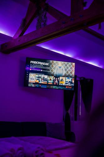 a tv in a room with purple lights at La suite BLR in Villemandeur