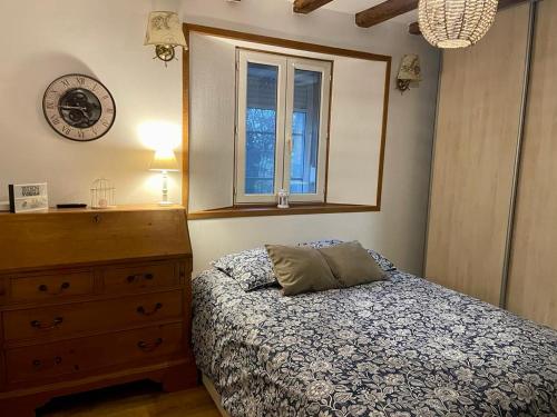 a bedroom with a bed and a dresser and a clock at Chez Isa et Geo in Laguian-Mazoux
