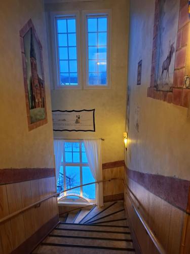 a hallway with a room with windows and a staircase at Hotell Örnen in Torsby