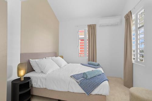 a white bedroom with a bed and a window at Casa Blue Marlin in Kralendijk