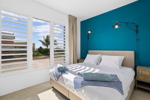 a bedroom with a large bed with a blue wall at Casa Blue Marlin in Kralendijk