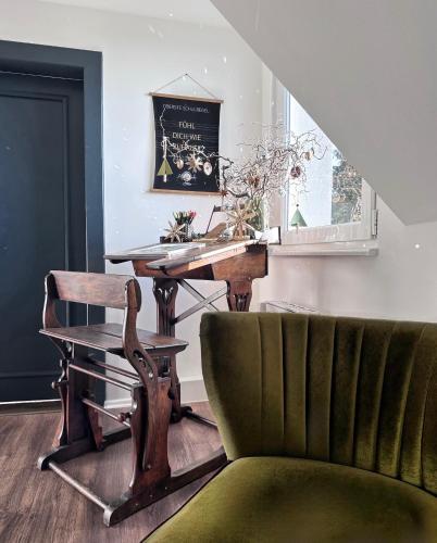 a living room with a green chair and a table at ALTE SCHULE WITTENBERG, 3 Ferienwohnungen für bis zu 12 Personen, an der Elbe, mit Garten in Lutherstadt Wittenberg