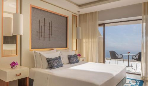 a bedroom with a large white bed and a balcony at Tivoli Carvoeiro in Carvoeiro