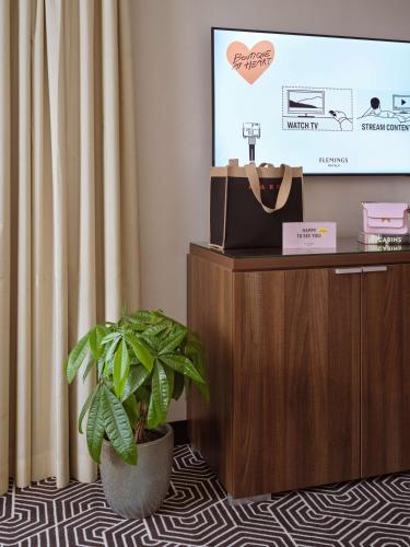 a potted plant sitting in front of a flat screen tv at Flemings Hotel Frankfurt Main-Riverside in Frankfurt/Main
