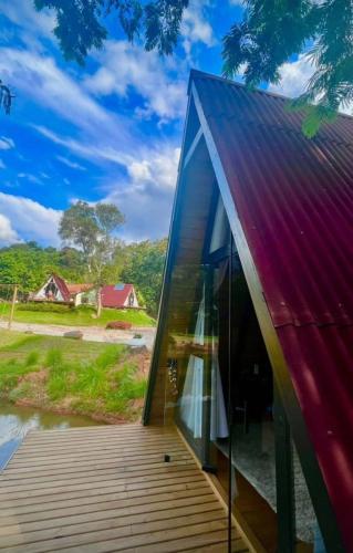 una casa in vetro con tetto rosso e terrazza in legno di Sitio Lar da Terra a São Roque