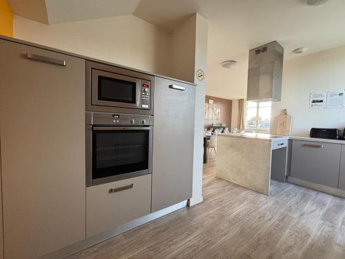 a kitchen with a stove and a microwave at Les sables d'or Grand apt lumineux bien équipé 1er étage vue panoramique sur campagne près superette, à 600 m plage proche Omaha Beach et pointe du Hoc parking gratuit, garage à disposition in Vierville-sur-Mer