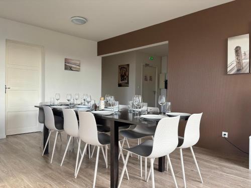 a dining room with a black table and white chairs at Les sables d'or Grand apt lumineux bien équipé 1er étage vue panoramique sur campagne près superette, à 600 m plage proche Omaha Beach et pointe du Hoc parking gratuit, garage à disposition in Vierville-sur-Mer