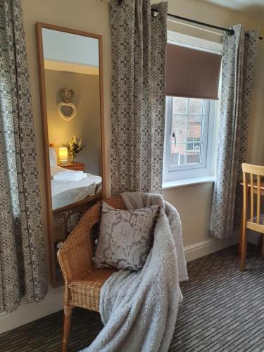 a bedroom with a mirror and a chair and a bed at Apple Blossom Guesthouse in Rempstone