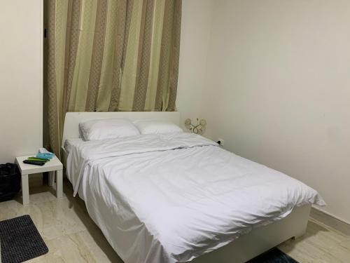 1 cama blanca en un dormitorio con mesa auxiliar en Comfort Suite Near Triumph Luxury Hotel, en El Cairo
