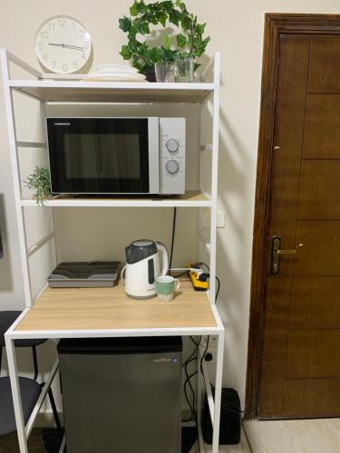 un microondas sentado en un estante junto a un escritorio en Comfort Suite Near Triumph Luxury Hotel, en El Cairo