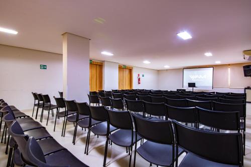 a conference room with chairs and a screen at Boulevard Suíte Hotel by WAM Experience in Caldas Novas