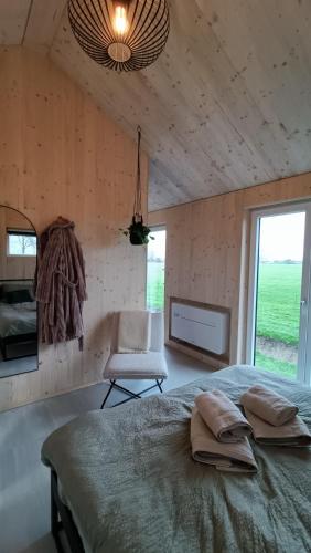a bedroom with a bed and a chair and a window at Boerenerf Lodge - Erf 1 in Kampen