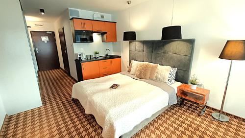 a bedroom with a large bed and a kitchen at 122 W PIĘCIOGWIAZDKOWYM ROYAL TULIP SAND 200m plaża DOBRUK APARTAMENTY ROMEK prywatny in Kołobrzeg