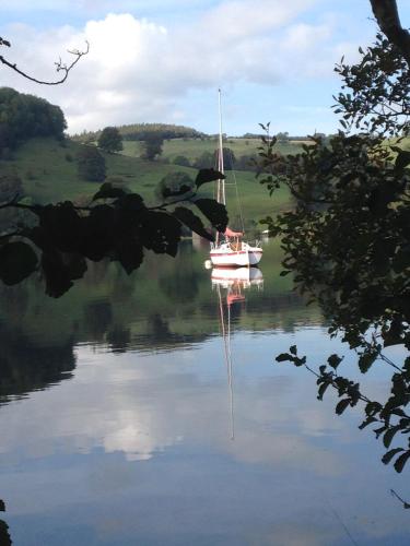 a boat on a lake with its reflection in the water at Rebels Hide -Self check in rooms in Penrith