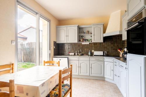 une cuisine avec des armoires blanches et une table dans l'établissement 128-Aux beaux volumes, proche plage, à Pornic