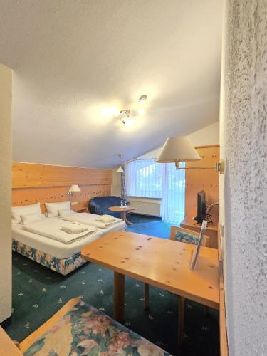 a hotel room with a bed and a table at Holzschuhs Schwarzwaldhotel in Baiersbronn
