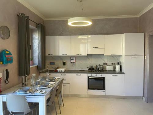a kitchen with white cabinets and a table with chairs at Luxury Apartment with Hot Tub in Is-Swieqi