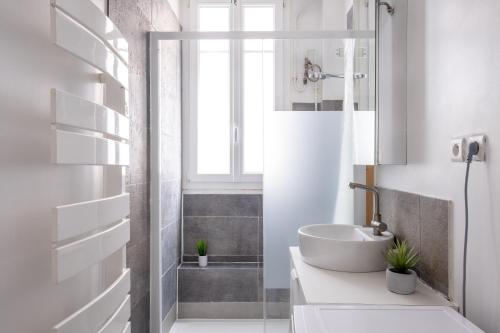 une salle de bain blanche avec un lavabo et une douche dans l'établissement Havre de Raffinement à Levallois-Perret, à Levallois-Perret