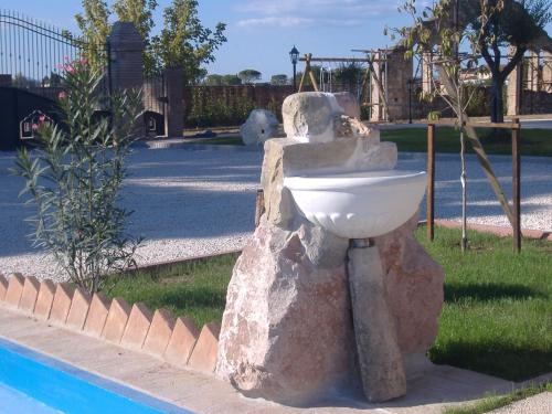 a statue of a sink next to a pool at Il Casale Della Fornace in Bastia Umbra
