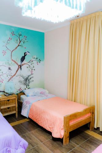 a bedroom with two beds and a bird painted on the wall at Las Moras Multiespacio in Cucha Cucha