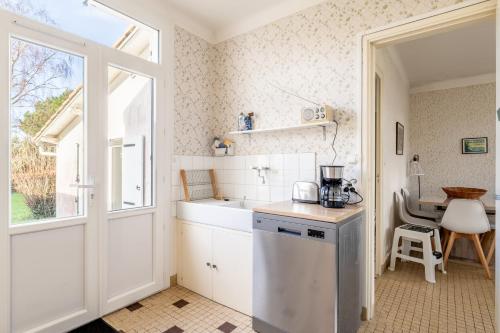 une cuisine avec des placards blancs, une fenêtre et une table dans l'établissement 910 - Maison 4, plage à pied, à Pornic