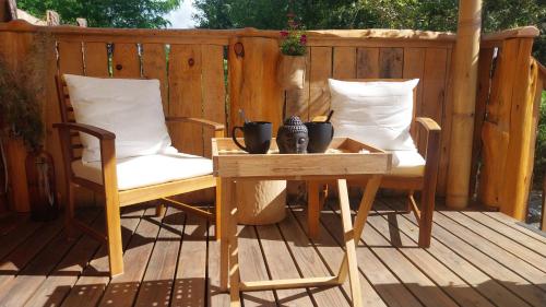 een houten terras met twee stoelen en een tafel op een veranda bij L'Entre2rêves in Saint-Maigrin