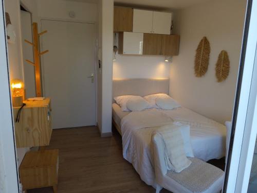 - une chambre avec un lit doté de draps blancs et d'une chaise dans l'établissement Studio - Les Voiles de La Baule, à La Baule