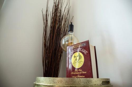 ein Buch und eine Glasflasche auf dem Tisch in der Unterkunft The Shakespeare Townhouse - Stratford upon Avon in Stratford-upon-Avon