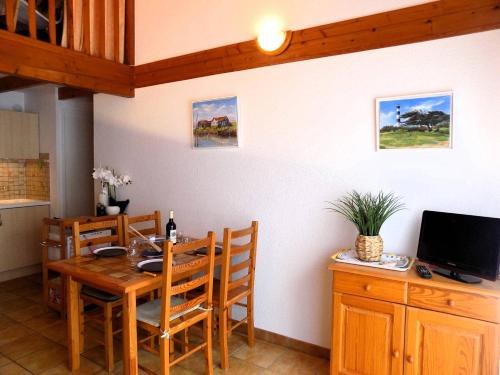 une salle à manger avec une table en bois et une télévision dans l'établissement Saint Palais sur Mer - APPARTEMENT Les Flots Bleus - PLAGE du BUREAU, à Saint-Palais-sur-Mer