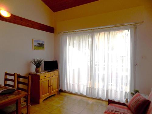 - un salon doté d'une grande fenêtre avec des rideaux blancs dans l'établissement Saint Palais sur Mer - APPARTEMENT Les Flots Bleus - PLAGE du BUREAU, à Saint-Palais-sur-Mer