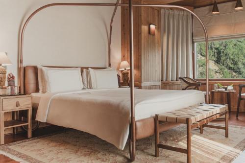 a bedroom with a canopy bed and a table at Brij Atmanya Bhowali, Nainital, A Luxury Mountain Escape in Nainital