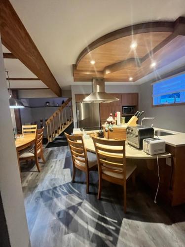 a kitchen and dining room with a table and chairs at Appartement Mont Édouard, Hébergement paisible à la montagne in LʼAnse-Saint-Jean