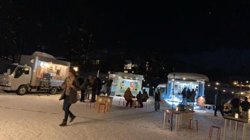 un grupo de personas caminando por la nieve por la noche en 白馬の小家ー202室, en Hakuba