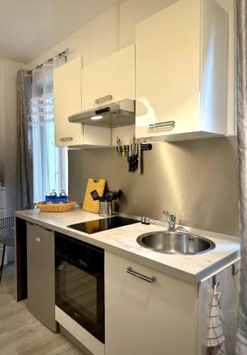 - une cuisine avec un évier et des placards blancs dans l'établissement Palais des Sources Vichy, à Vichy