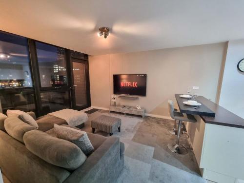 a living room with a couch and a tv at Canal Side Flat by City SuperHost in Manchester