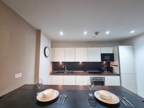 a kitchen with a table with two plates and wine glasses at Canal Side Flat by City SuperHost in Manchester