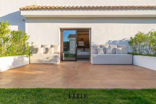 a patio with white couches in front of a building at Lussuosa Villa con piscina a Porto Rotondo in Cugnana
