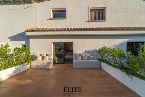 a house with a patio with couches in front of it at Lussuosa Villa con piscina a Porto Rotondo in Cugnana