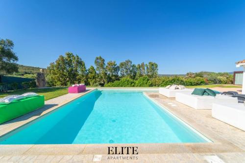 a swimming pool with blue water and white furniture at Lussuosa Villa con piscina a Porto Rotondo in Cugnana