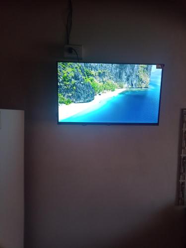 a flat screen tv hanging on a wall with a beach at el escondido in Villa Cura Brochero