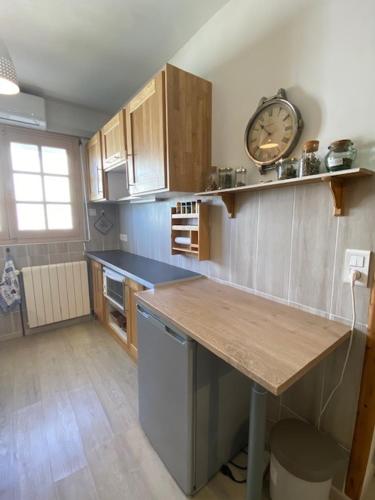 une cuisine avec un comptoir et une horloge au mur dans l'établissement Maison de ville 4pers avec jardinet et garage - V0549, à Vias