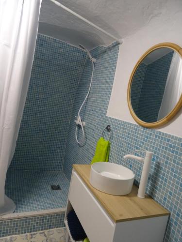 a bathroom with a sink and a shower with a mirror at Cueva mágica de Raspay in Raspay