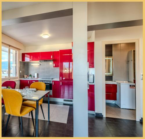 a kitchen with red cabinets and a table and chairs at Chez Damien I T2 I Gaīllard in Gaillard