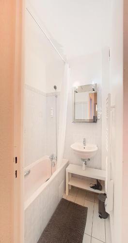 La salle de bains blanche est pourvue d'un lavabo, d'une baignoire et d'un miroir. dans l'établissement Palladium - Studio 40m2 - 10 min Palais - Climatisé, à Cannes