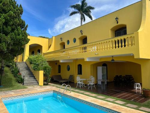 a yellow house with a swimming pool in front of it at Casas de férias in Guarujá