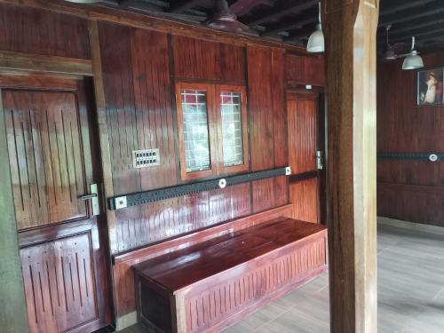 a wooden bench in a room with two windows at Kailasahomestay & Ayurvedic Spa in Pūvār